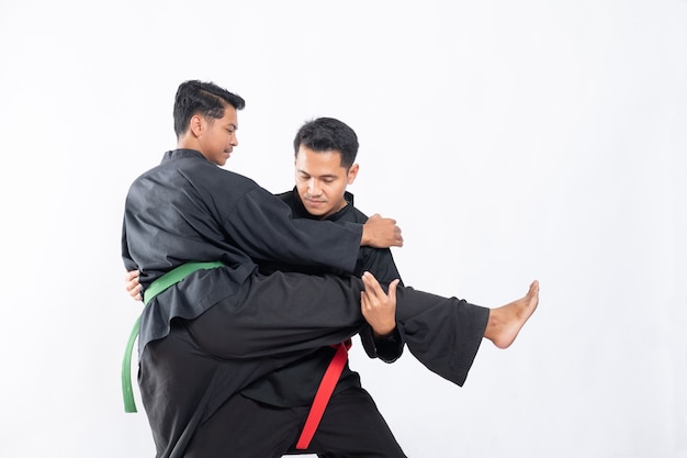 Deux combattants en uniforme de pencak silat noir se battent dans des écluses et des claques