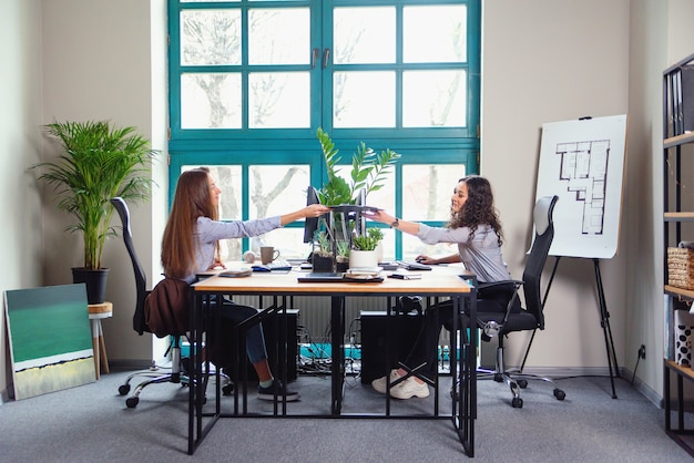Deux concepteurs féminins caucasiens travaillant dans un bureau moderne. Une fille donne une palette de couleurs à une autre.