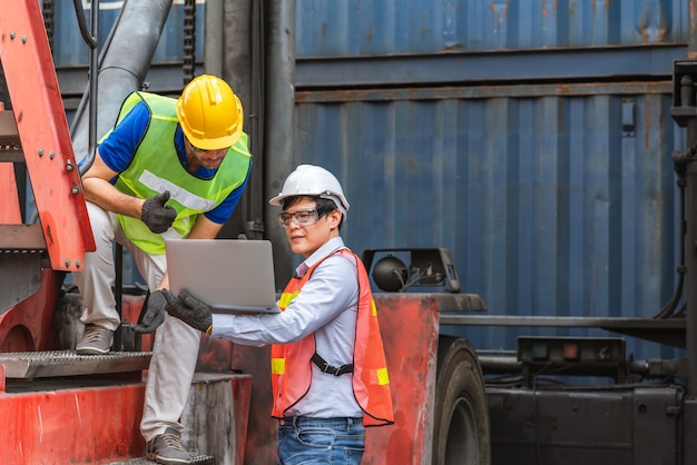 Deux contremaîtres avec ordinateur portable de vérification de la position de chargement des conteneurs fort de fret cargo à l'expédition de conteneurs de fret