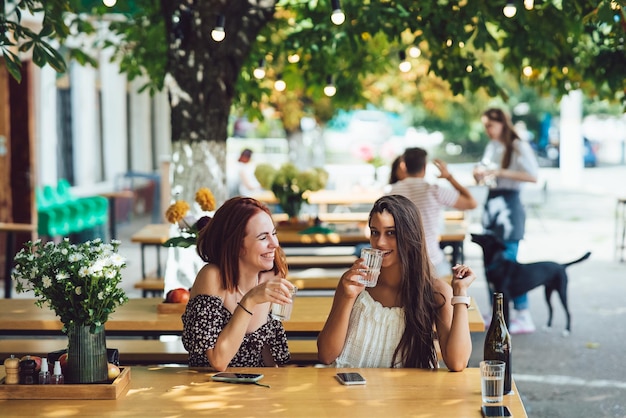 Deux copines de belles jeunes femmes parlant dans un café en plein air