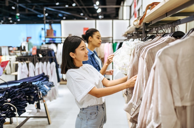 Deux copines choisissant des vêtements dans un magasin de vêtements