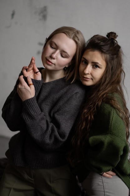 Deux copines européennes blonde et brune posent en pulls verts et gris