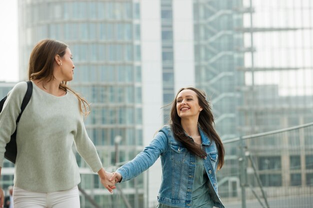 Deux copines marchant dans la ville, main dans la main