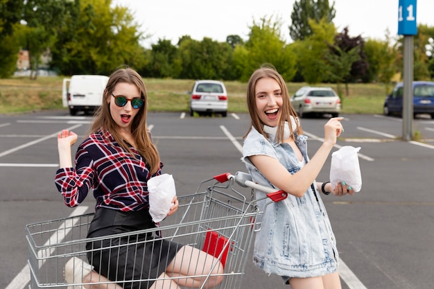 Deux copines s'amusent dans un parking de supermarché.