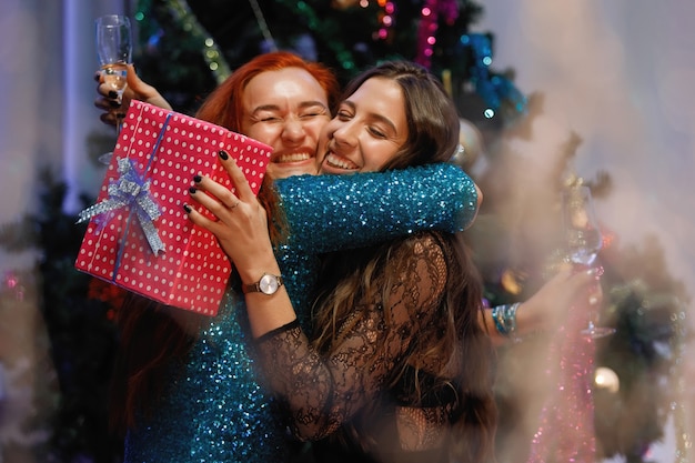 Deux copines s'offrent des coffrets cadeaux près d'un sapin de Noël.