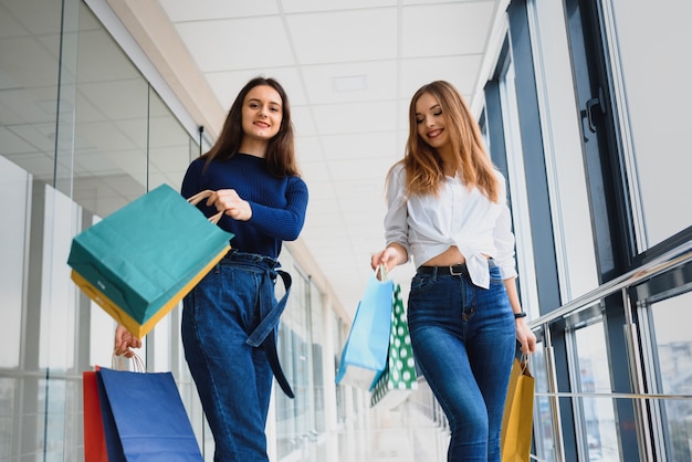 Deux copines sur shopping à pied sur le centre commercial avec des sacs