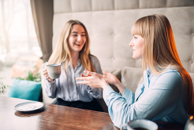 Deux copines souriantes boit du café au café