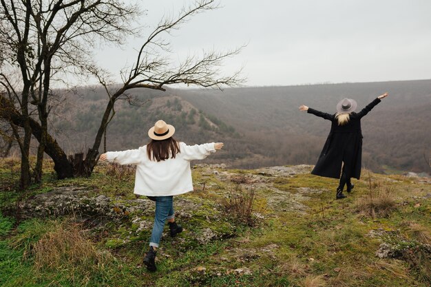 Deux copines vont avec les mains en regardant les montagnes.