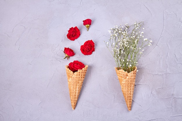 Deux cornets de crème glacée gaufrée avec des fleurs vue de dessus à plat