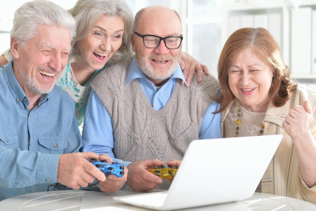 Deux couples âgés assis à table et jouant à un jeu informatique