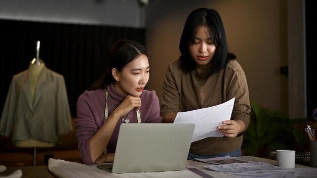 Deux couturières asiatiques discutent du patron de leur nouvelle collection en studio