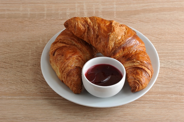 Deux croissant doré avec de la confiture sur une assiette