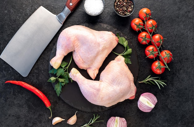 deux cuisses de poulet crues avec des épices et des herbes sur un fond de pierre