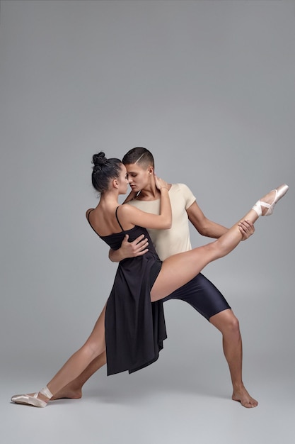 Deux danseurs de ballet modernes athlétiques posent sur un fond de studio gris