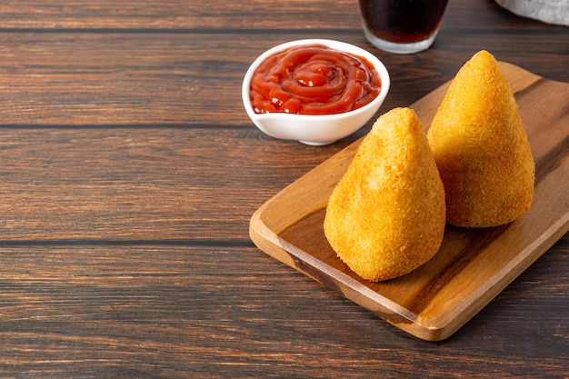 deux délicieuses coxinhas sur une planche à découper en bois au-dessus de la table