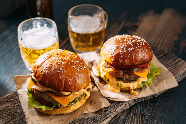 Deux délicieux hamburgers de boeuf sur une table en bois près de deux verres de bière froide