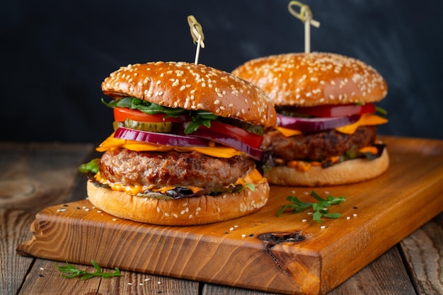 Deux délicieux hamburgers faits maison de fromage de boeuf et de légumes sur une vieille table en bois gras malsain pour...