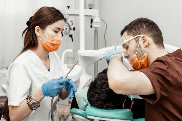 Deux Dentistes Soignent Un Patient. Uniforme Professionnel Et équipement D'un Dentiste. Santé équiper Un Lieu De Travail De Médecins. Dentisterie