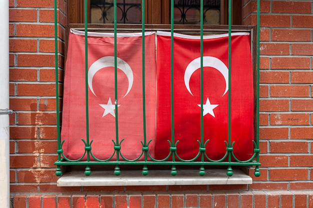 Photo deux drapeau turc ondulant dans la fenêtre avec le mur de briques de grille