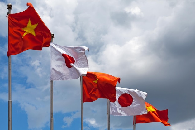 Deux drapeaux japonais et trois drapeaux vietnamiens flottant au sommet de leurs mâts