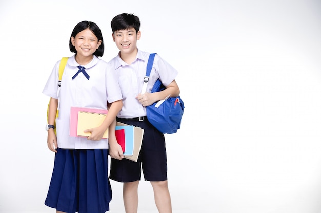 Deux écoliers asiatiques souriants avec de la papeterie colorée,