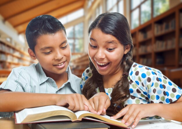 Deux écoliers hispaniques s'amusent à étudier dans une bibliothèque scolaire