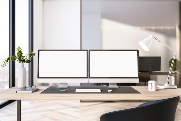 Deux écrans d'ordinateur blancs vides sur le bureau de bureau à l'intérieur avec vue sur la ville pendant la journée Modèle d'entreprise Maquette Rendu 3D