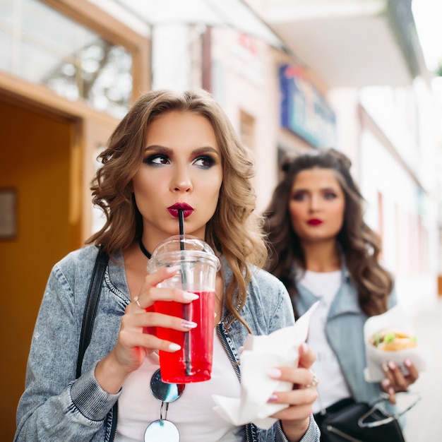 Deux élégantes filles swag marchant dans la rue avec de la restauration rapide et des boissons.