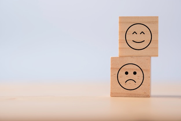 Deux émotions de joyeux et de triste qui impriment des sérigraphies sur des cubes en bois Enquête sur l'expérience client et concept de rétroaction de satisfaction.