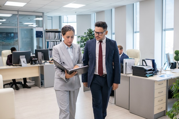 Deux employés élégants discutant du nouveau contrat détenu par une femme