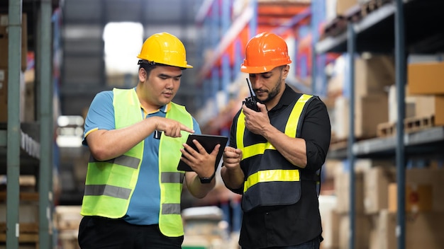 Deux employés d'entrepôt parlent de logistique et de distribution lors de la vérification des stocks d'entrepôt