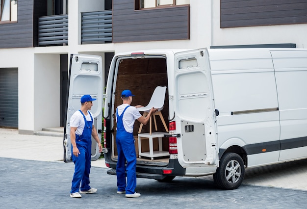 Deux employés d'une entreprise de déménagement chargent des cartons et des meubles dans un minibus