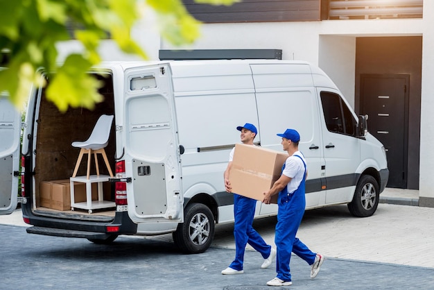 Deux employés d'une entreprise de déménagement chargent des cartons et des meubles dans un minibus