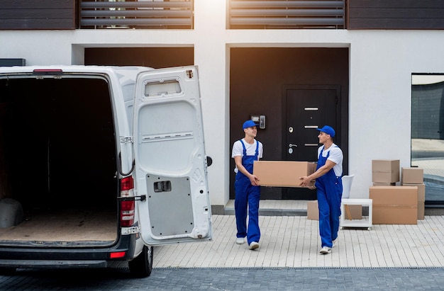 Deux employés d'une entreprise de déménagement chargent des cartons et des meubles dans un minibus