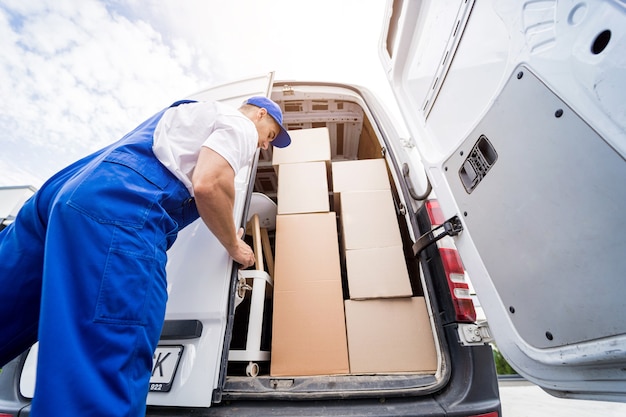 Deux employés d'une entreprise de déménagement déchargeant des cartons et des meubles d'un minibus