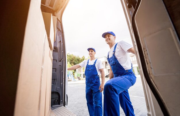 Deux employés d'une entreprise de déménagement déchargeant des cartons d'un minibus