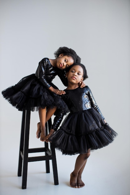 Deux enfants africains en robes noires embrassant en studio