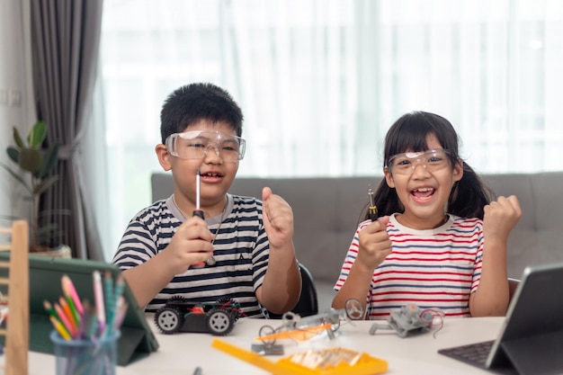 Deux enfants asiatiques s'amusant à apprendre à coder ensemble à apprendre à distance à la maison STEM science enseignement à domicile éducation amusement distanciation sociale isolement nouveau concept normal