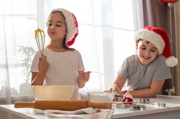 Deux enfants en bonnets rouges cuisinent joyeusement des cookies dans la cuisine