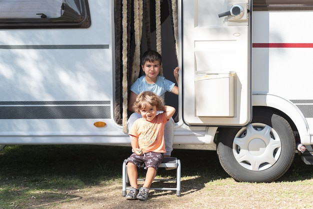 Deux enfants caucasiens jouent et passent des vacances alternatives dans une caravane