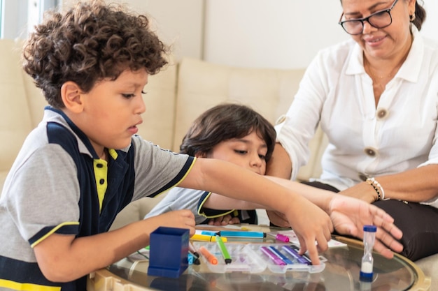 Deux enfants colorient à la maison avec leur grand-mère