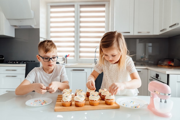 Deux enfants décorent des cupcakes