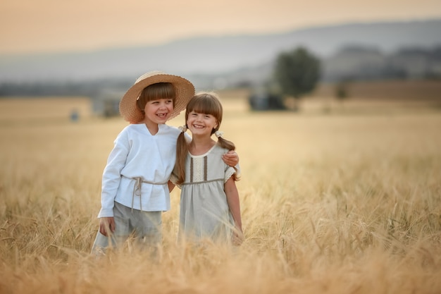 Deux enfants un garçon et une fille d'âge préscolaire marchent ensemble dans un champ de blé