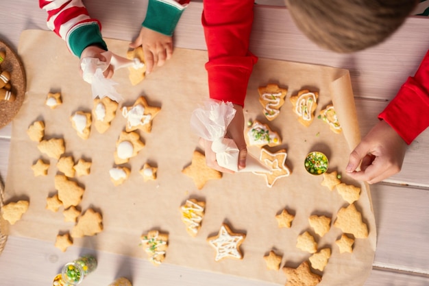 deux enfants garçon et fille en pyjama cuisinant du pain d'épice festif dans la cuisine. vue de dessus