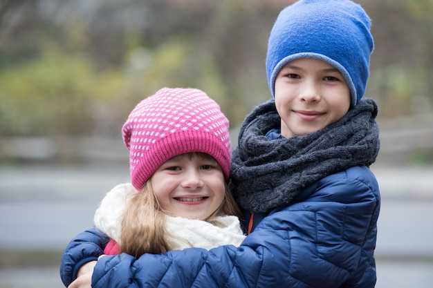 Deux enfants garçon et fille s'embrassant à l'extérieur portant des vêtements chauds par temps froid d'automne ou d'hiver.
