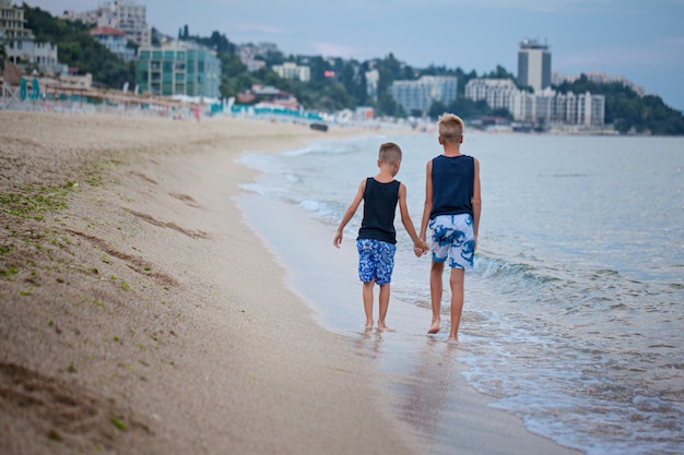 Deux enfants garçons marchant sur la mer plage été, heureux meilleurs amis jouant. Vue arrière