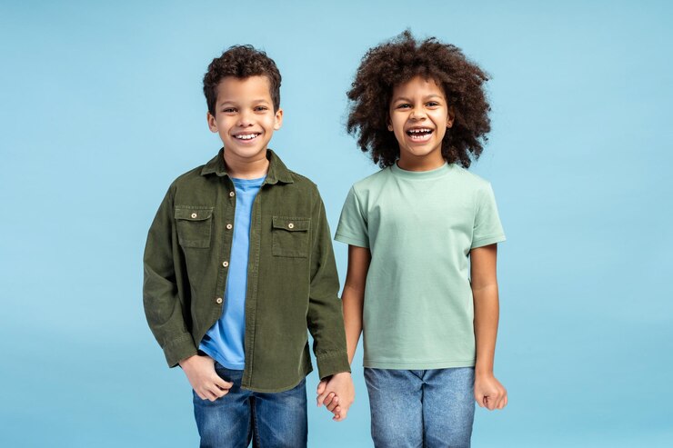 Photo deux enfants heureux posant en studio tout en se tenant par la main et en regardant la caméra en souriant.