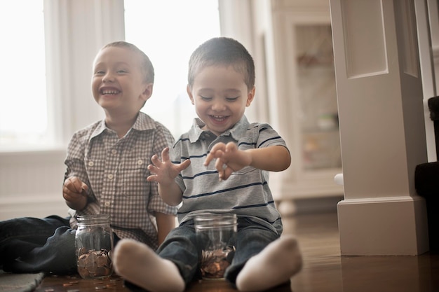 Deux enfants jouant avec des pièces de monnaie en les déposant dans des bocaux en verre