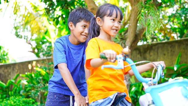Deux enfants jouant à vélo dans le jardin derrière la maison