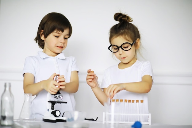 Deux enfants mignons à la leçon de chimie faisant des expériences sur fond blanc